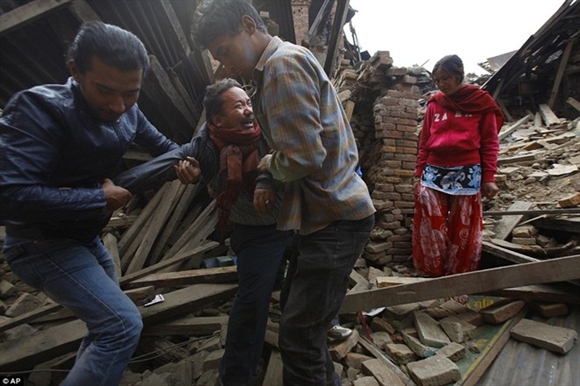 Người dân đưa một người đàn ông ra khỏi ngôi nhà đổ nát sau trận động đất. Tuy nhiên, mẹ của anh ta đã bị chôn vùi dưới những lớp gạch. Ảnh: AP