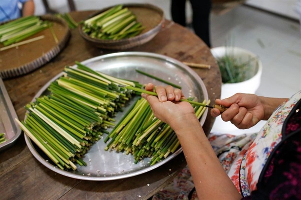A worker makes straws from grass at the 3T workshop in Long An province. Photo: Reuters