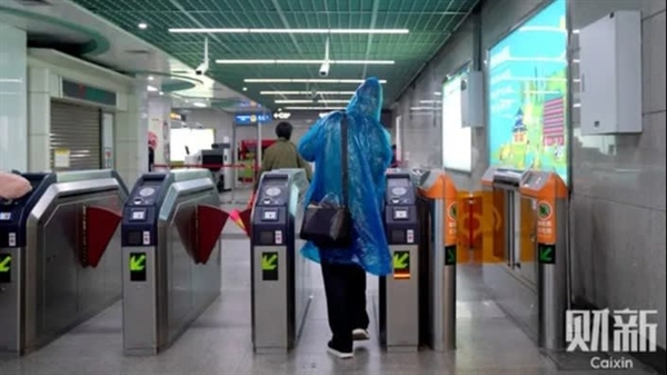 Một hành khách mang áo mưa bước qua trạm xe điện ngầm ở Quảng Châu. Nguồn: Caixin