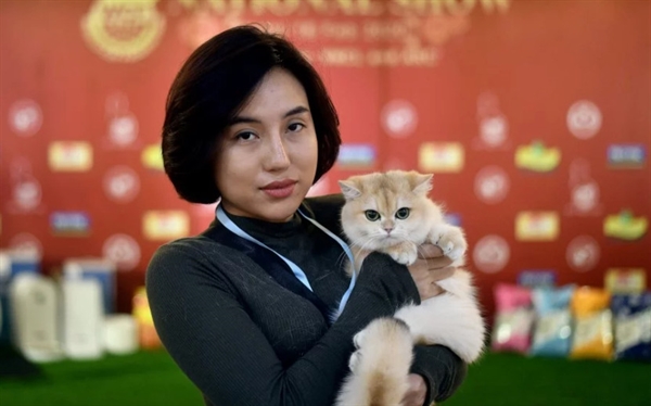 A participant poses with her cat Uslada, a British shorthair breed during Vietnam's first national cat show in Hanoi. -AFP