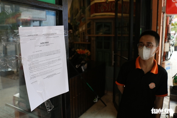 An employee looks at an announcement for ‘takeaway service only’ posted on the door of a coffee shop in District 1, Ho Chi Minh City, Vietnam, March 29, 2020. Photo: Ngoc Phuong / Tuoi Tre